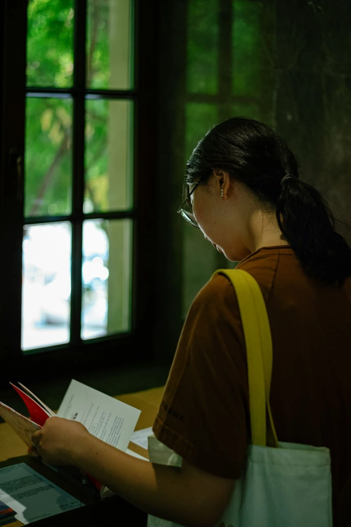 a woman standing in front of a window holding a piece of paper